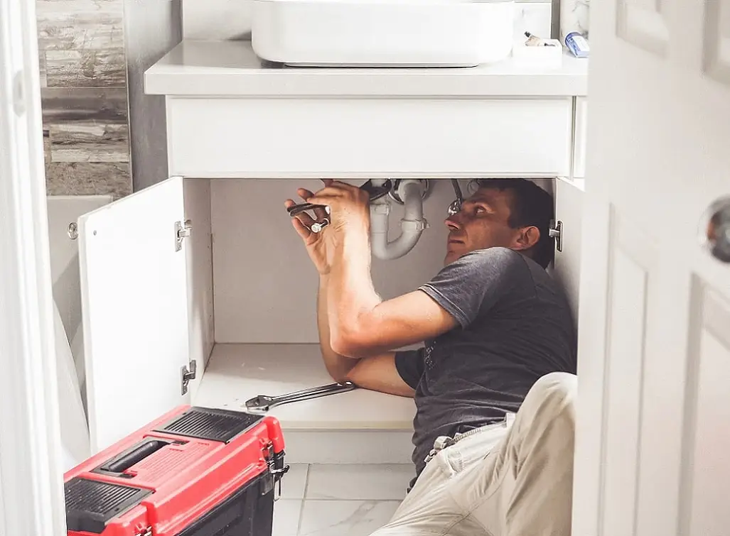 EZO plumber dealing with an emergency leak in a kitchen