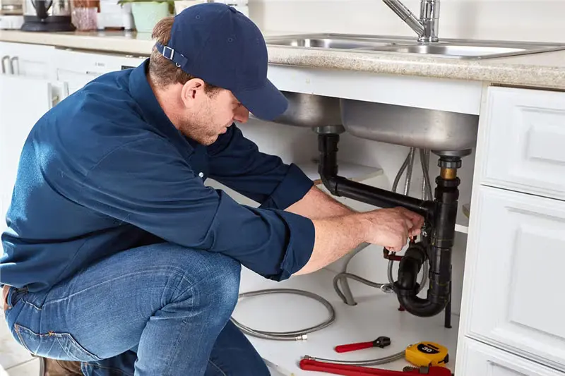 Close-up of EZO plumber repairing a leaking copper pipe under a sink
